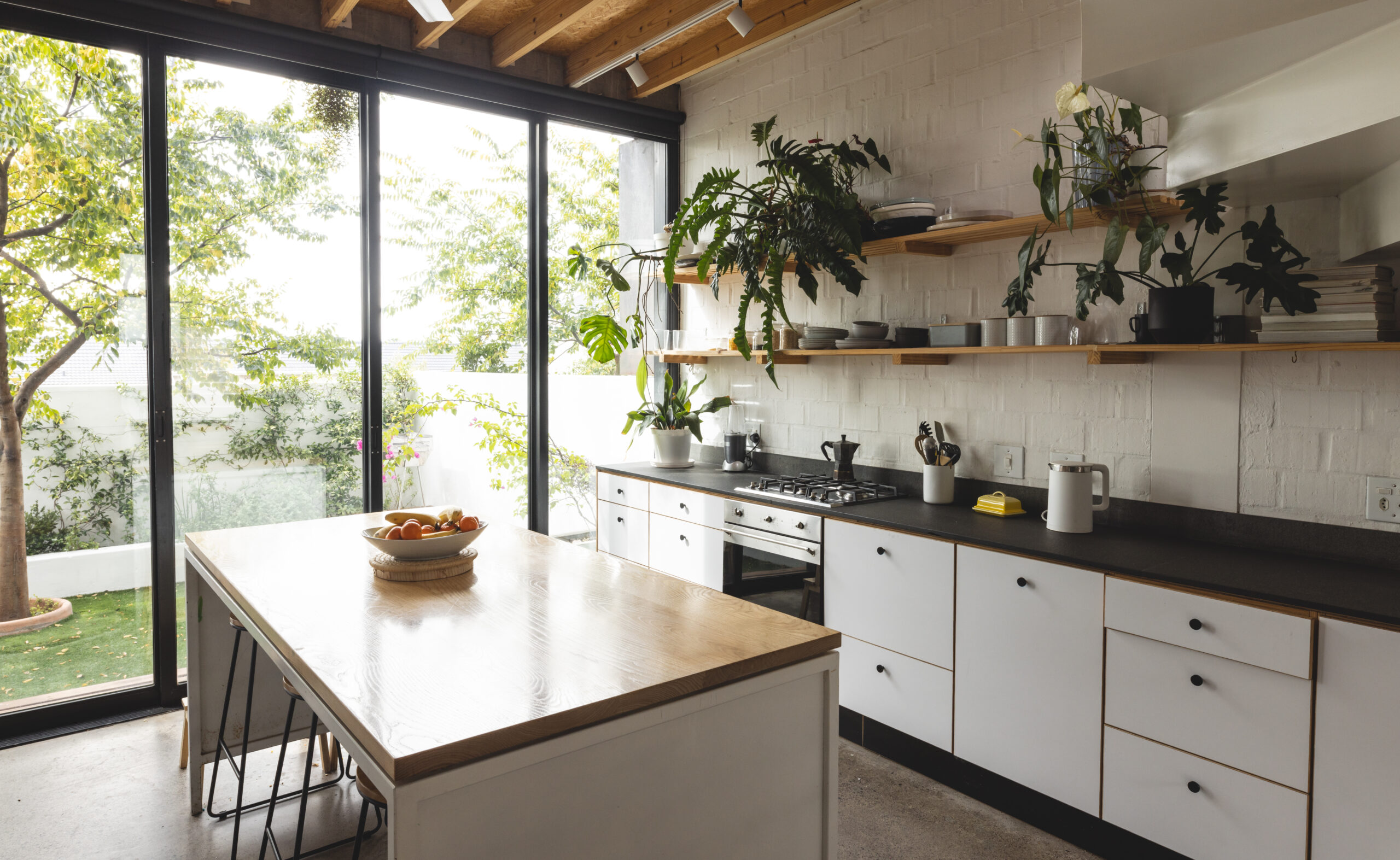 View of modern home kitchen interior with french windows to small garden. Real estate, domestic life and interior design